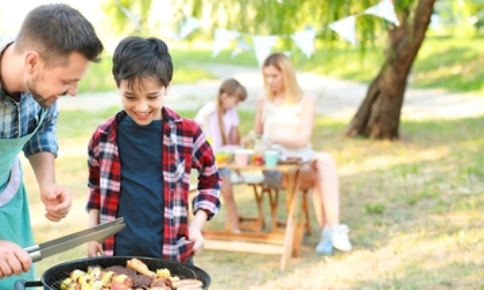 Kind und Mann grillen zusammen
