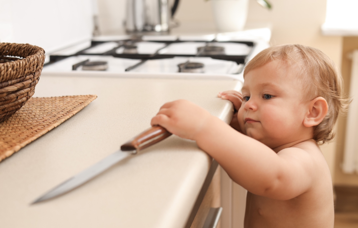 Baby greift nach Messer auf Arbeitsplatte
