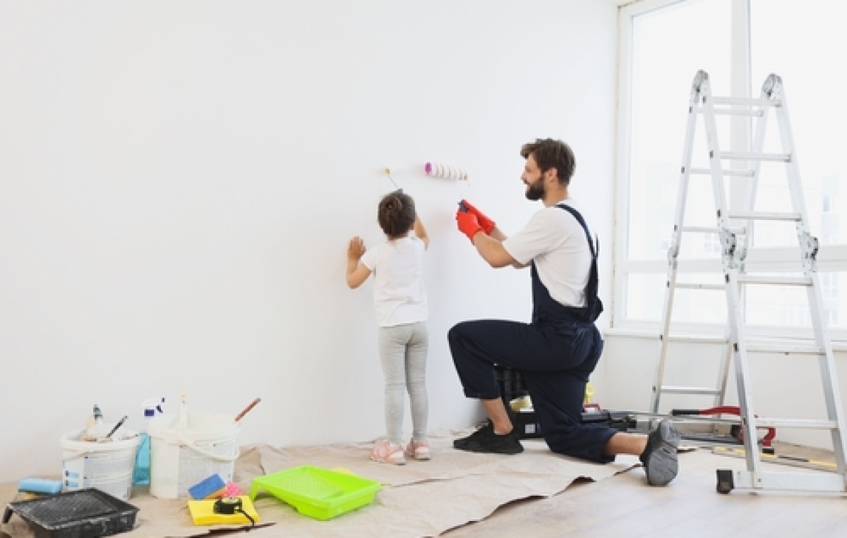 Kind und Mann streichen eine Wand