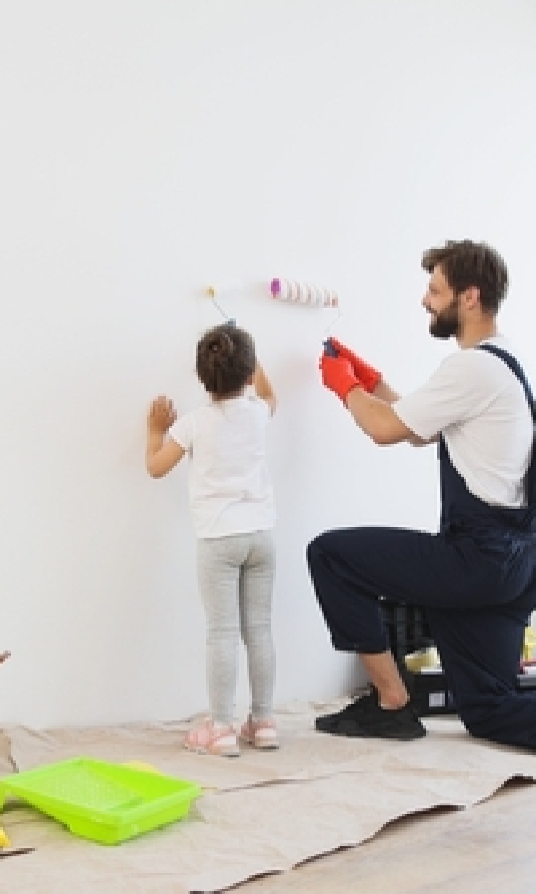 Kind und Mann streichen eine Wand