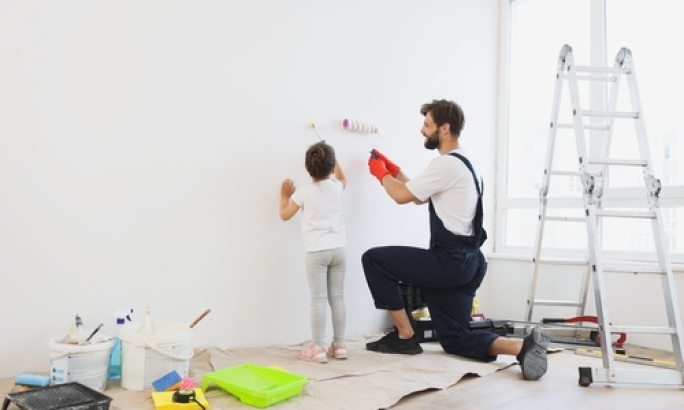 Kind und Mann streichen eine Wand