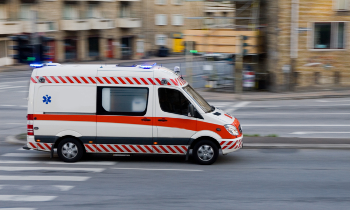 Ein Rettungswagen mit eingeschaltetem Blaulicht fährt schnell durch eine Stadtstraße.