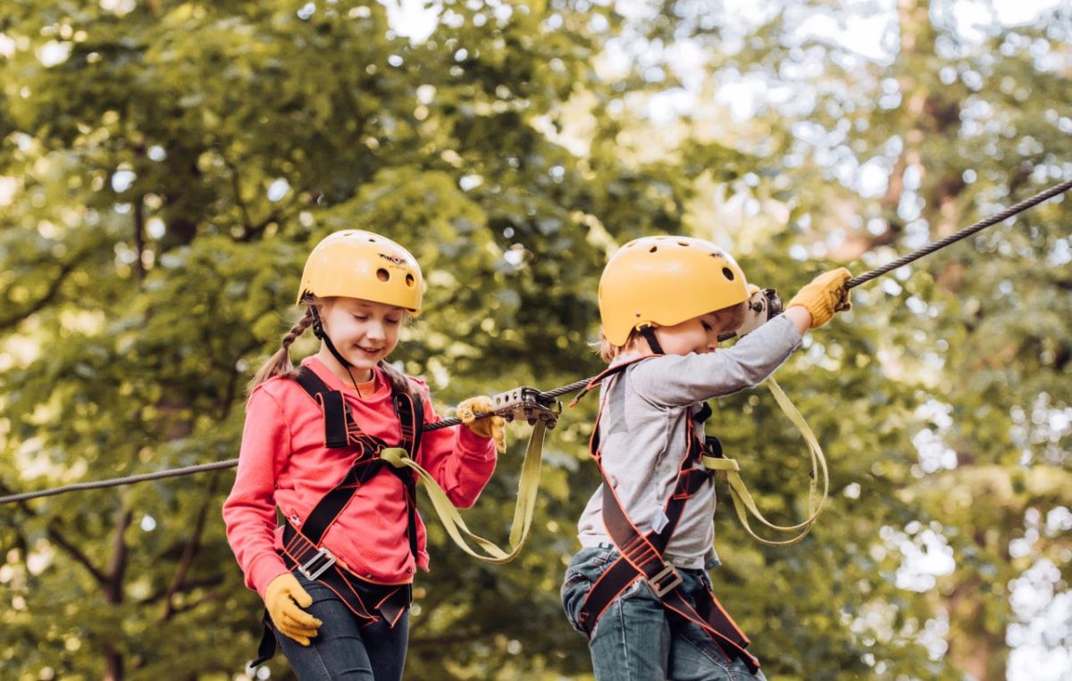 Kinder beim Klettern im Hochseilgarten mit Ausrüstung