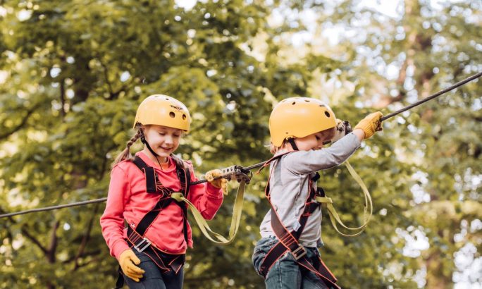 Kinder beim Klettern im Hochseilgarten mit Ausrüstung