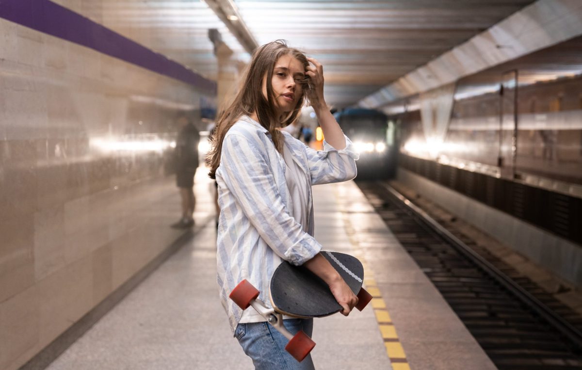 Mädchen mit Skateboard am Bahnsteig