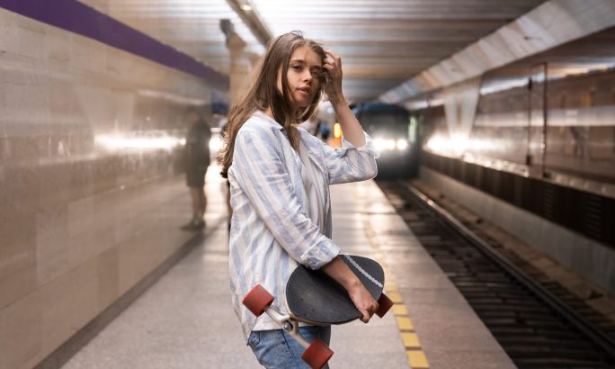 Mädchen mit Skateboard am Bahnsteig