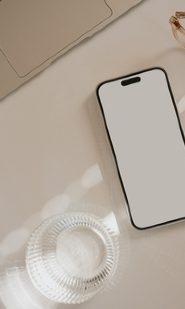 Smartphone liegt zwischen Laptop, Brille und Glas
