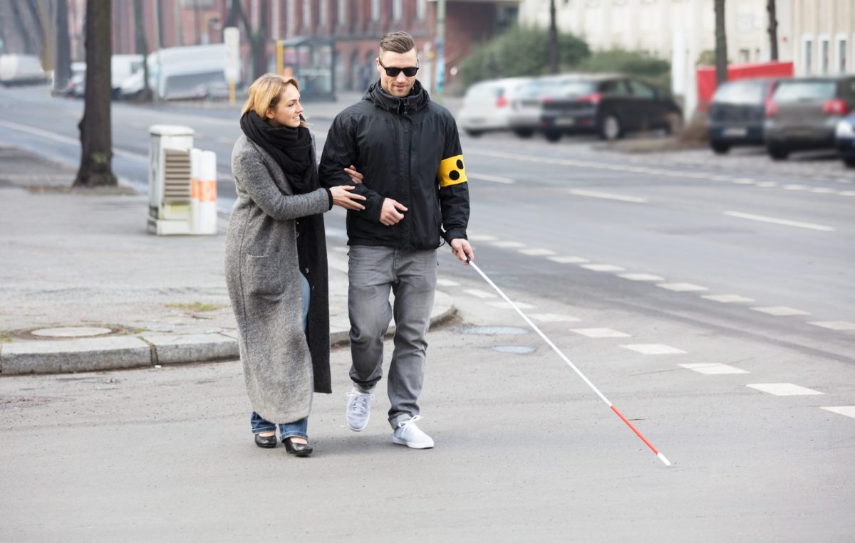 Blinder Mann wird über die Straße geholfen