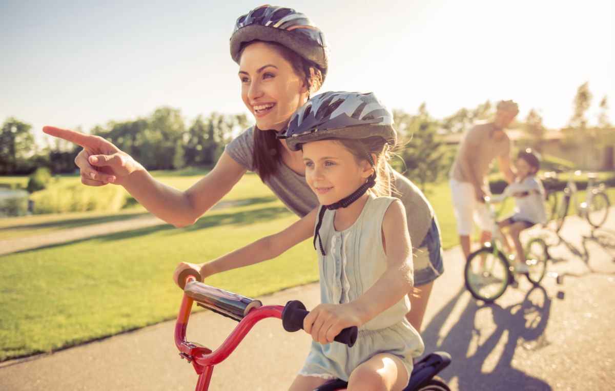 Mutter bringt Tochter das Fahrradfahren bei.