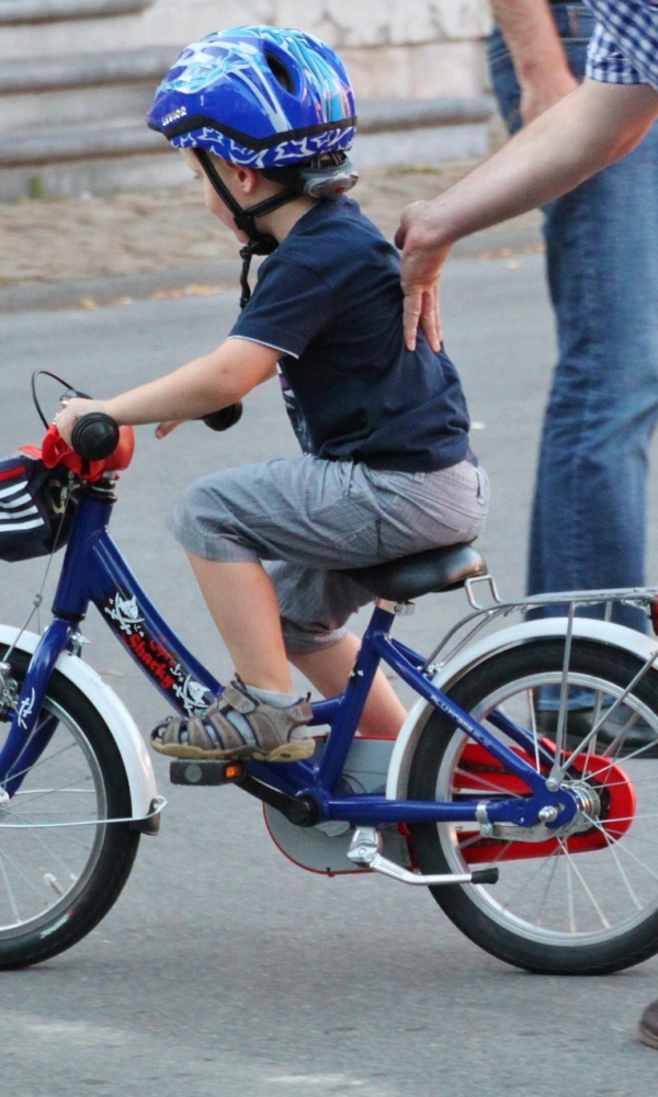 Eltern üben mit Kind Fahrrad fahren